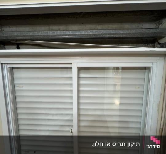 חלון עם תריסים לבנים במצב סגור